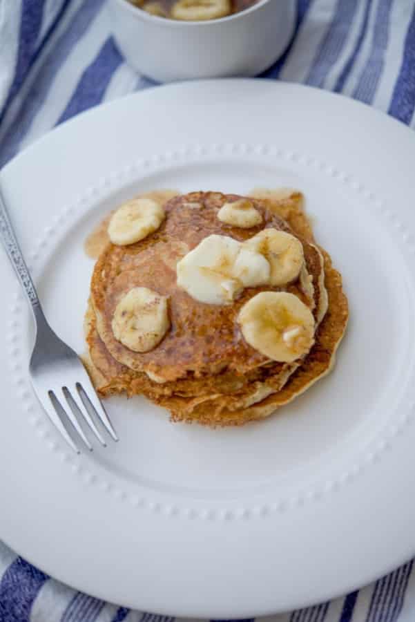 Pancakes made with rolled oats, flour, milk, eggs and fresh bananas topped with banana maple syrup is a delicious way to start the day.