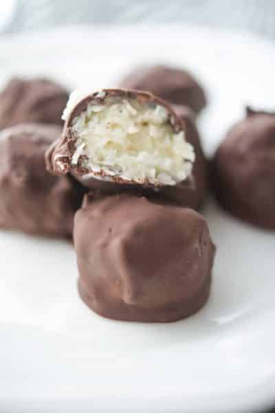 Chocolate covered coconut truffles on a white plate.