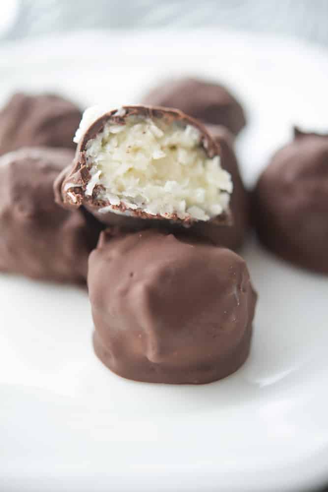 Chocolate covered coconut truffles on a white plate. 