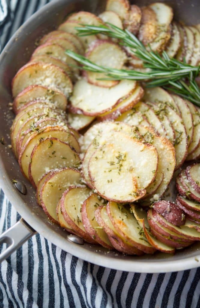 Parmesan Crusted Potato Gratin made in a skillet with layered red potatoes, butter, fresh rosemary and grated Parmesan cheese. 