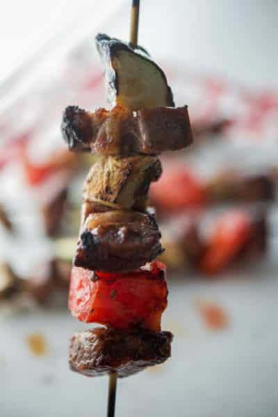 A close up of beef on skewers with vegetables.
