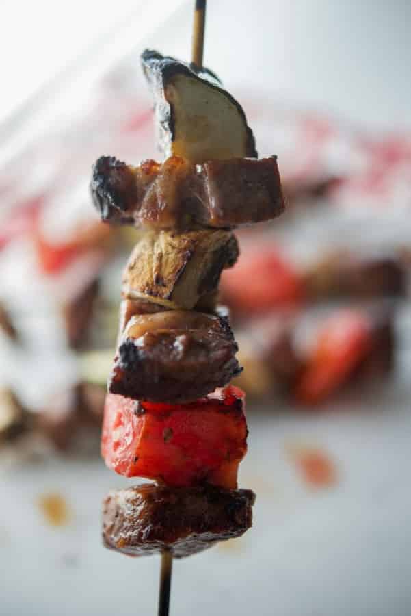 A close up of beef on skewers with vegetables. 