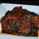 grilled strip steaks on a white plate