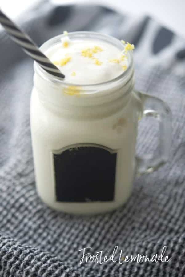 A close up of Frosted Lemonade in a clear glass mug with a straw. 