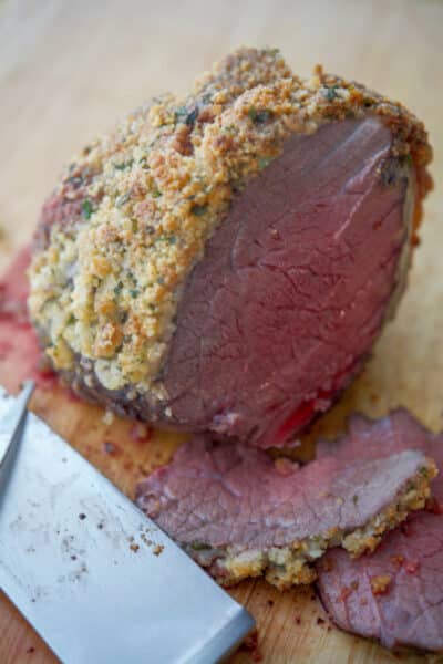 A piece of Parmesan Encrusted Roast Beef on a cutting board with