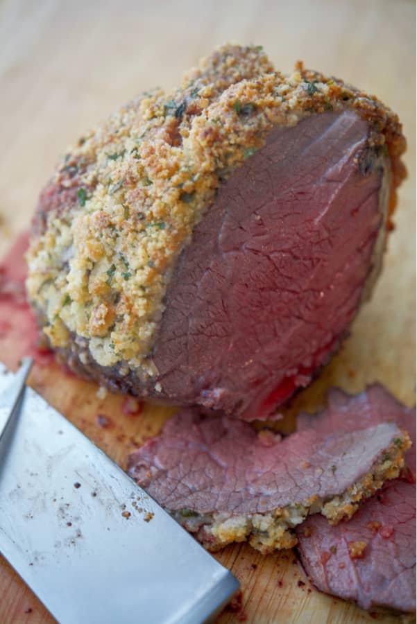 A piece of Parmesan Encrusted Roast Beef on a cutting board with 