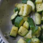 Fresh garden zucchini squash sautéed in a skillet on top of the stove in rosemary butter is a tasty, quick vegetable side dish. 