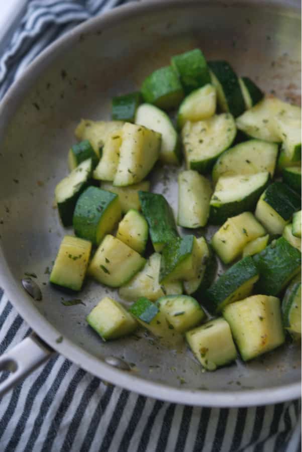Fresh garden zucchini squash sautéed in a skillet on top of the stove in rosemary butter is a tasty, quick vegetable side dish. 