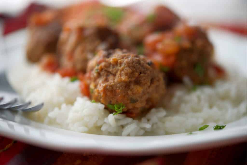A close up of a plate of food with rice and Mexican Meatballs. 