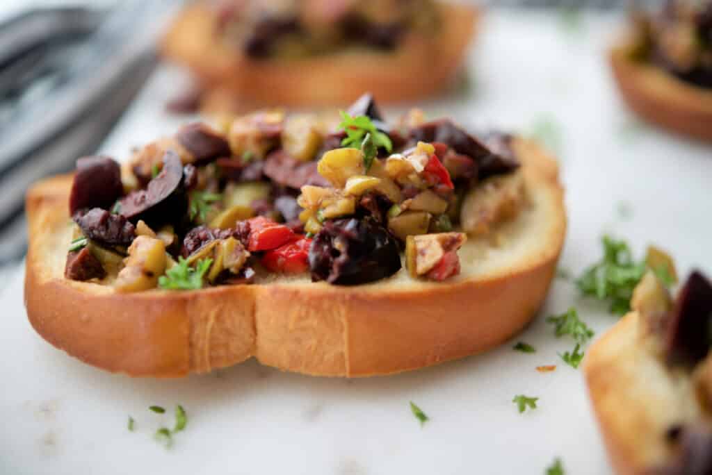 A close up of a plate of food with Olives on bread