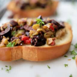 A close up of a plate of food with Olives on bread
