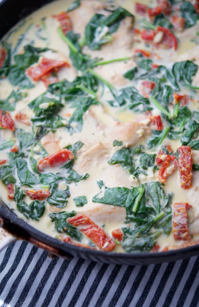 Creamy Tuscan Chicken made with boneless chicken pan seared in a skillet tossed with fresh spinach and sun dried tomatoes in an alfredo sauce.