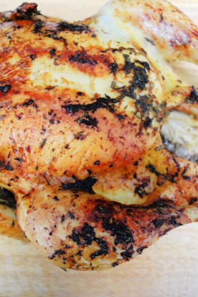 Roasted whole chicken with grapefruit and herbs on a cutting board.