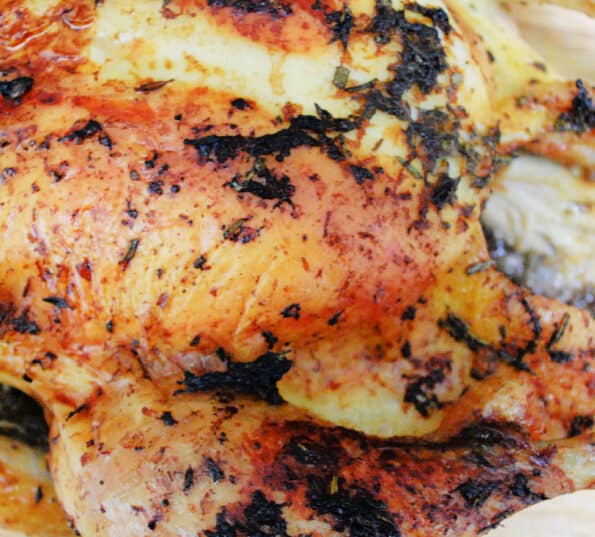 Roasted whole chicken with grapefruit and herbs on a cutting board.