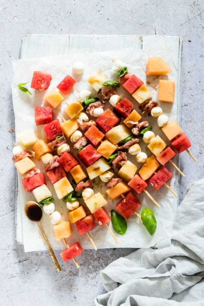 A bunch of food on a table, with watermelon skewers