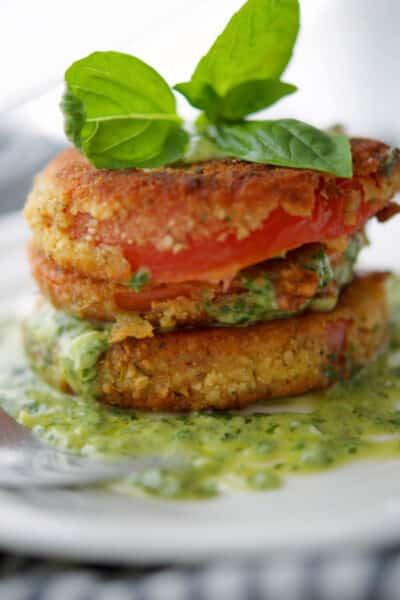 Fried tomatoes with pesto crema on a white plate