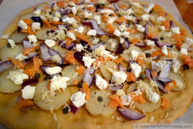 A pizza covered in salmon, cheese and toppings