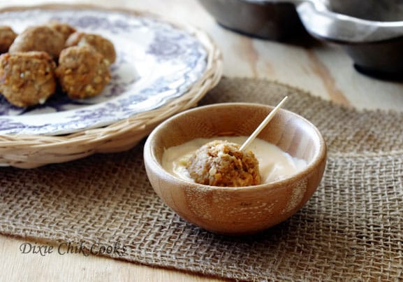 Salmon Meatballs on a toothpick dipped in sauce. 