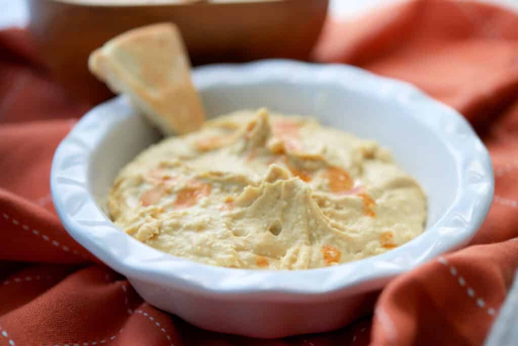 Buffalo Hummus in a bowl with a pita chip