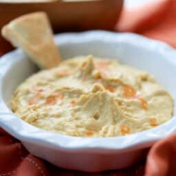 Buffalo Hummus in a bowl with a pita chip