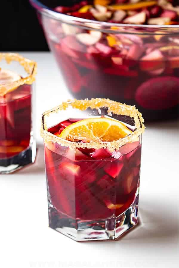 Sangria in a glass with orange zest on the rim. 