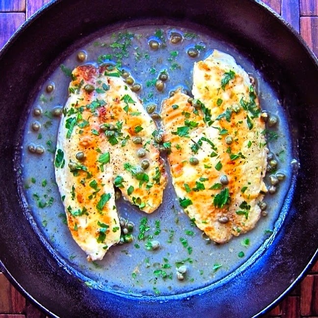 A pan of pizza on a blue plate, with Tilapia and Piccata