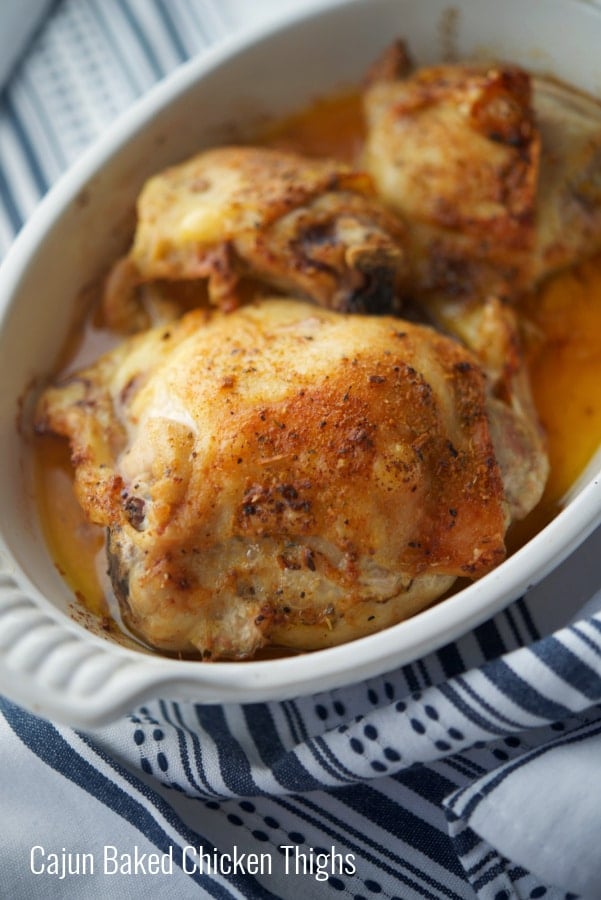 Cajun seasoned chicken thighs in a white baking dish. 