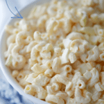 Deviled Egg Macaroni Salad in white bowl with spoon and name on photo.