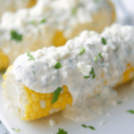 Corn on the cob on a plate with cajun lime crema.