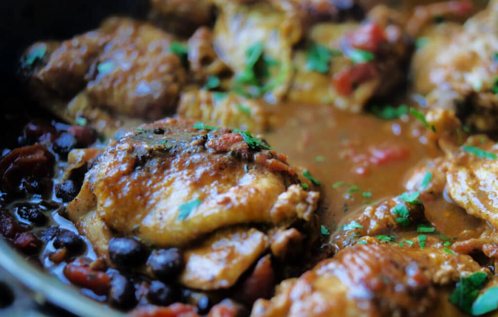 A close up of Mexican chicken with black beans in a skillet