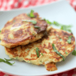 A photo of potato fritters with mozzarella and basil on a plate.