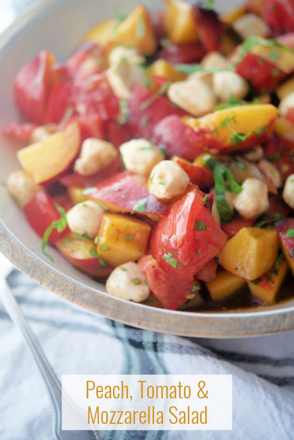 Peaches, tomatoes and mozzarella cheese in a wooden bowl. 