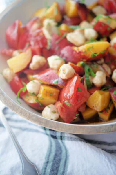 Fresh peaches, tomatoes and cheese in a bowl.