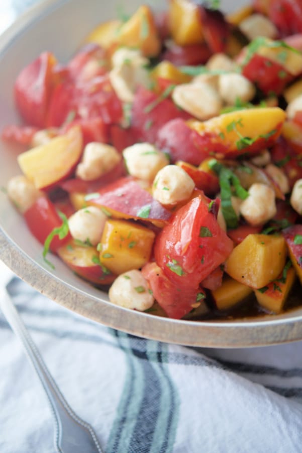 Fresh peaches, tomatoes and cheese in a bowl.