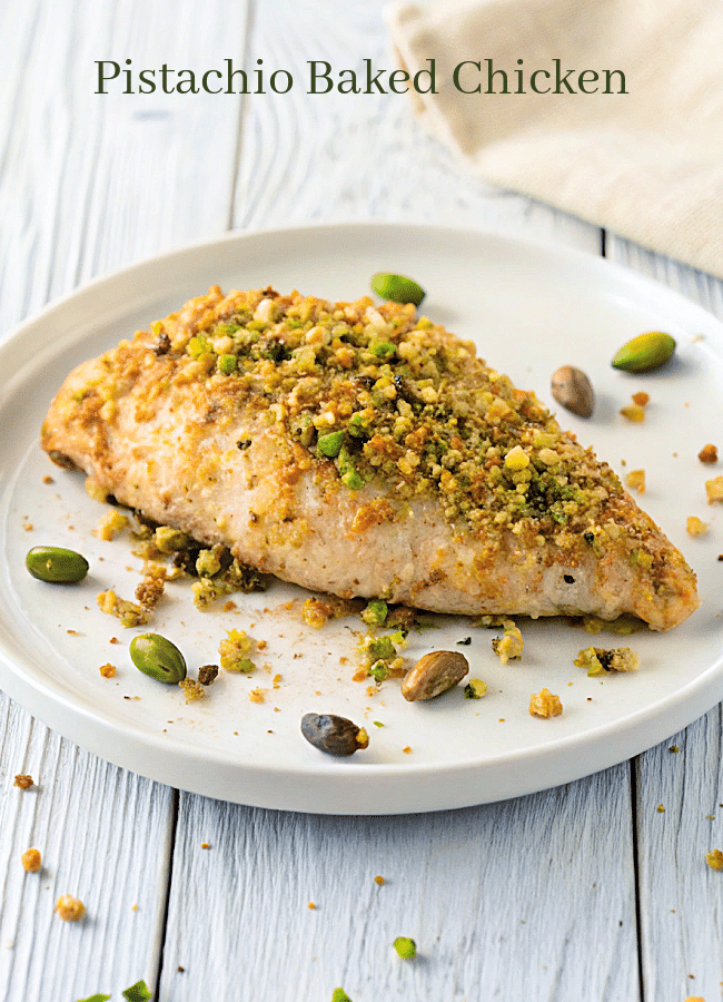 a plate with a piece of chicken topped with breadcrumbs and pistachios