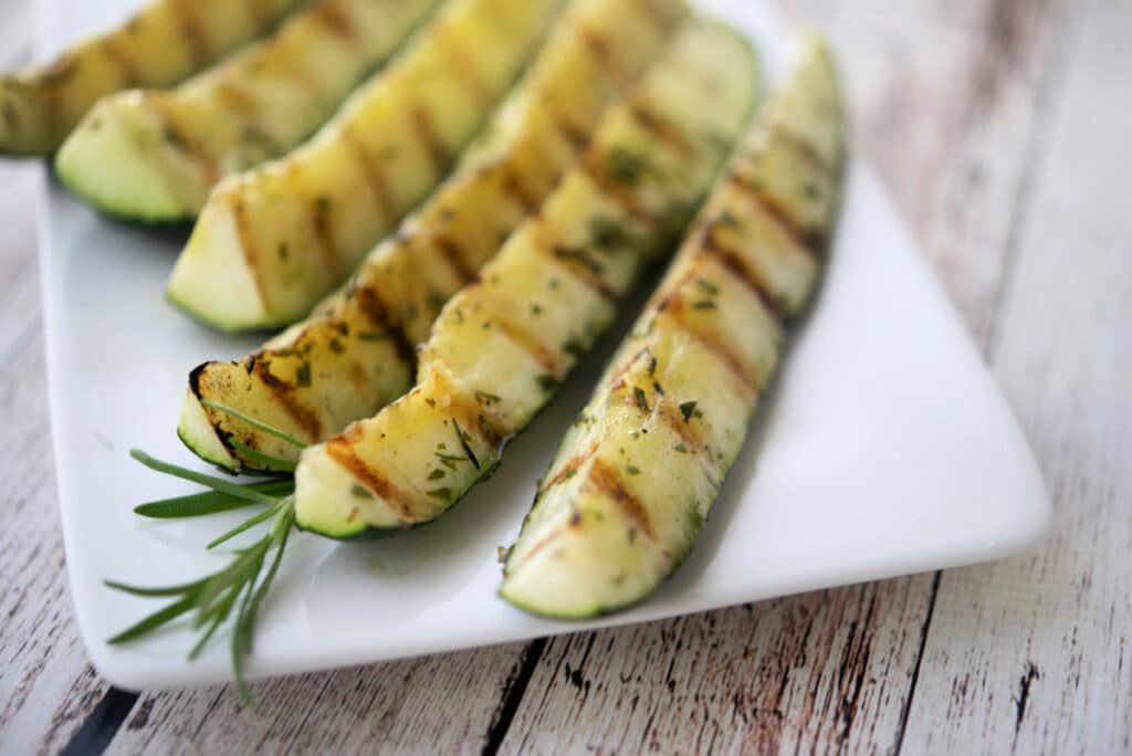 A close up of zucchini on a plate with rosemary