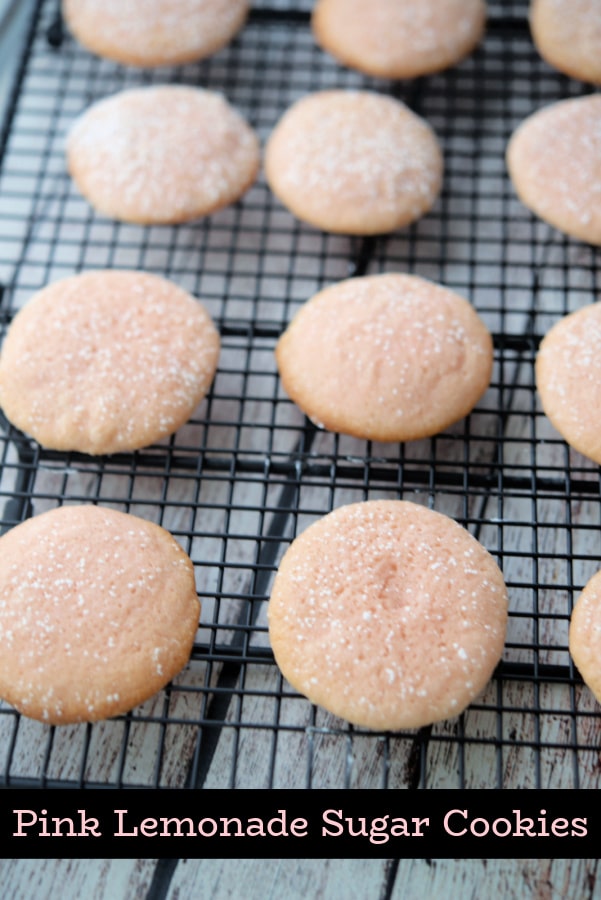 Pink sugar cookies on a black baking rack. 