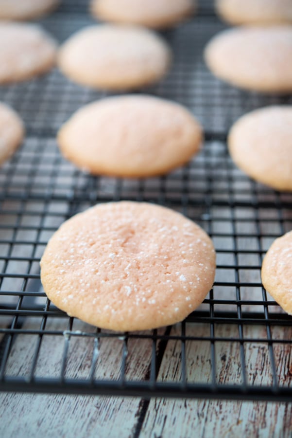 A row of pink lemon sugar cookies on a cooling rack. 