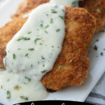 A close up of pork cutlets with lemon sauce on a plate.