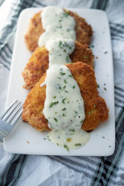 Fried pork cutlets on a white plate with lemon sauce