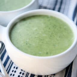 A close up of potato spinach soup in a white soup crock