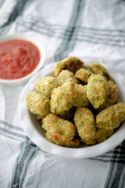 Broccoli tots in a dish with sauce.