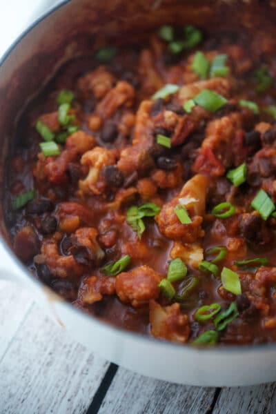 Vegetarian chili in a white dutch oven with cauliflower