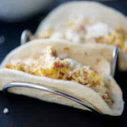 A close up of breakfast tacos on a taco stand