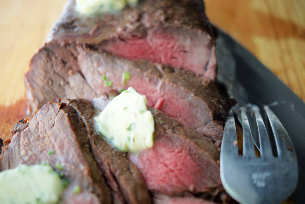 A close up of sliced steak with butter. 