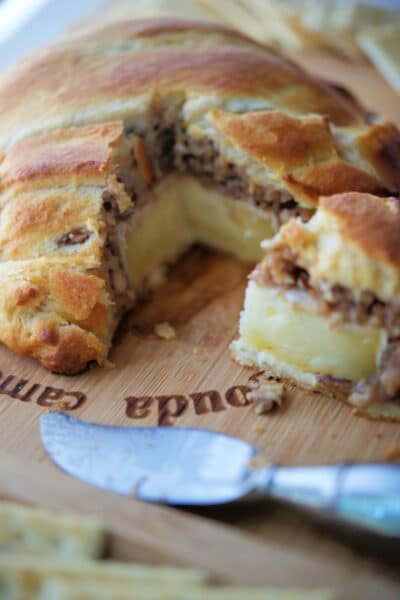 A slice of baked brie cut from the wheel of cheese.