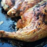 A close up of a spatchcock chicken on a sheet pan