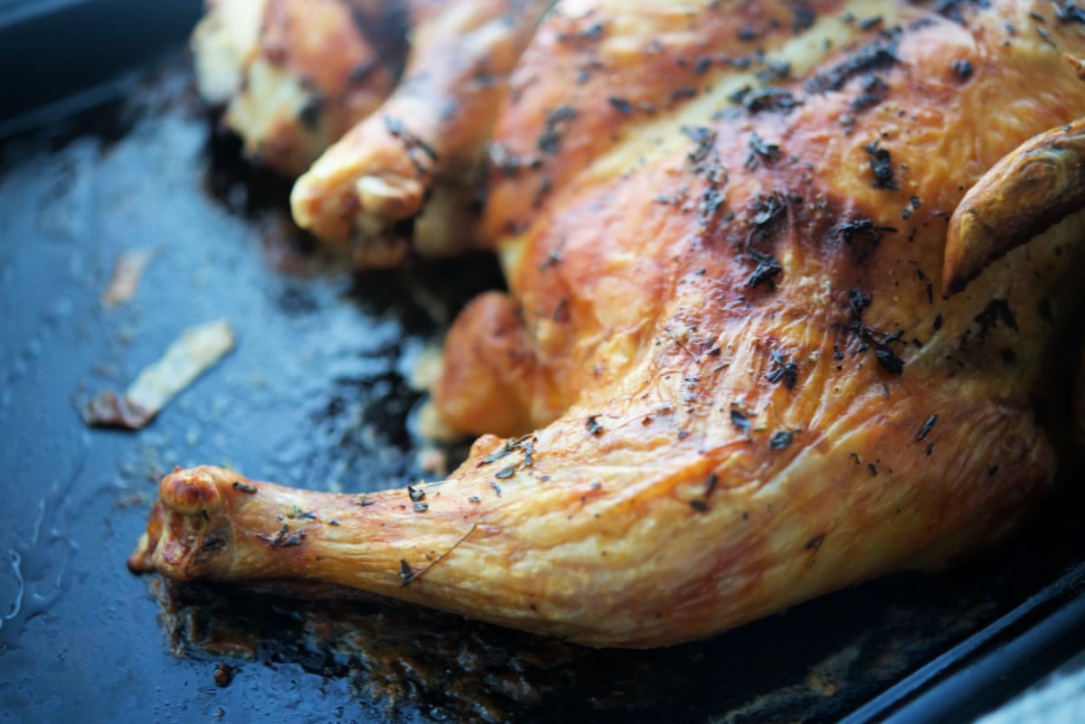 A close up of a spatchcock chicken on a sheet pan