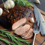 a cooked beef brisket on a dark wooden cutting bord