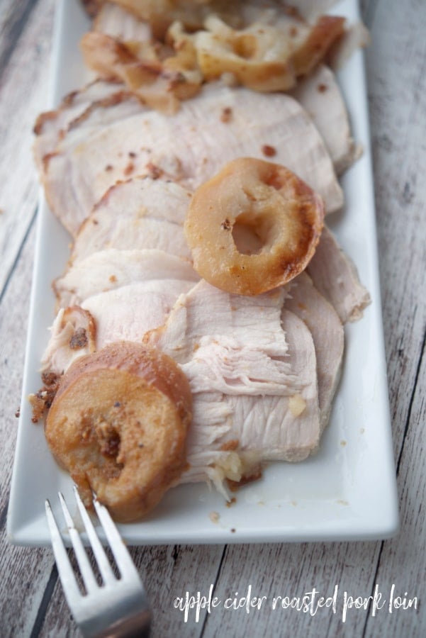 Sliced pork loin with apples on a white platter